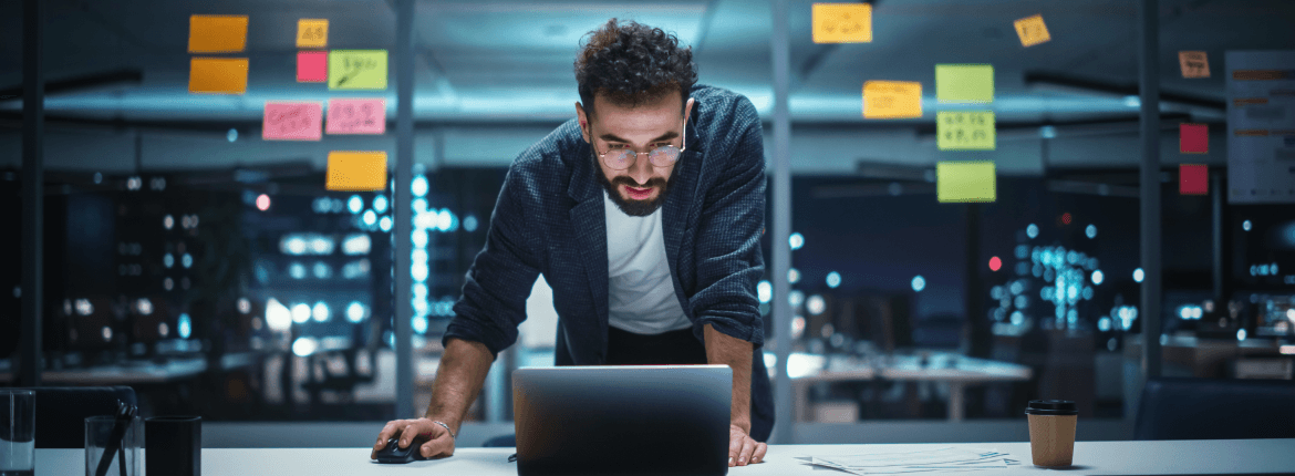 A software developer focused on his laptop, working diligently in a modern office environment