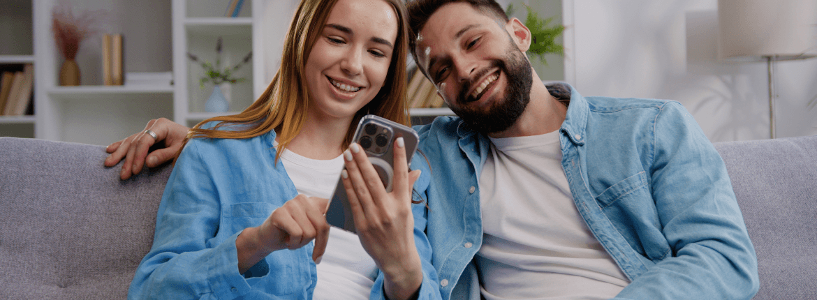 Young couple smiling and reviewing finances in their phone