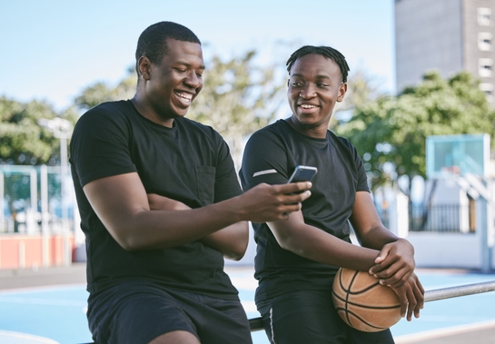 Male brothers on their phone spending time together, siblings or friends bonding as a family outdoors.