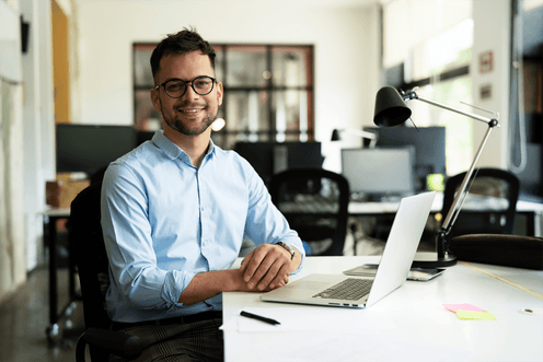 Data warehouse male manager smiling with a laptop and a pen in an office