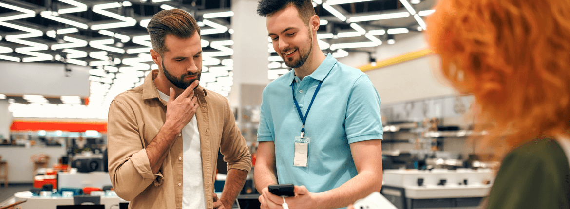 A male retail employee sharing information to a potential male customer at a retail store