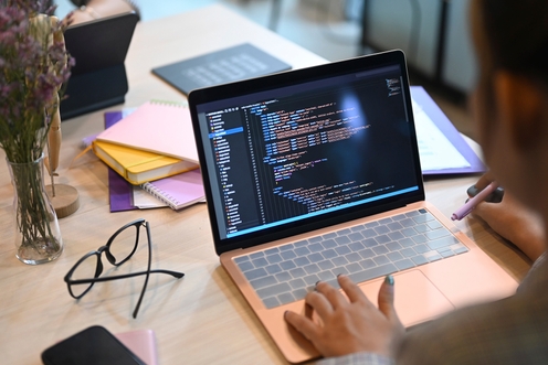 A female developer writing code on a laptop in a modern workspace